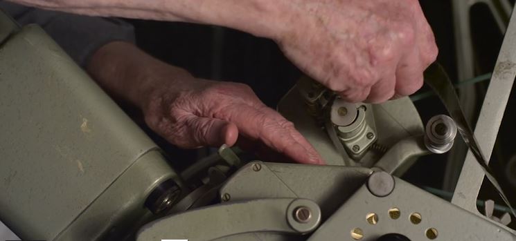 A still from a short Moviola documentary, showing a person threading film into the machine.
