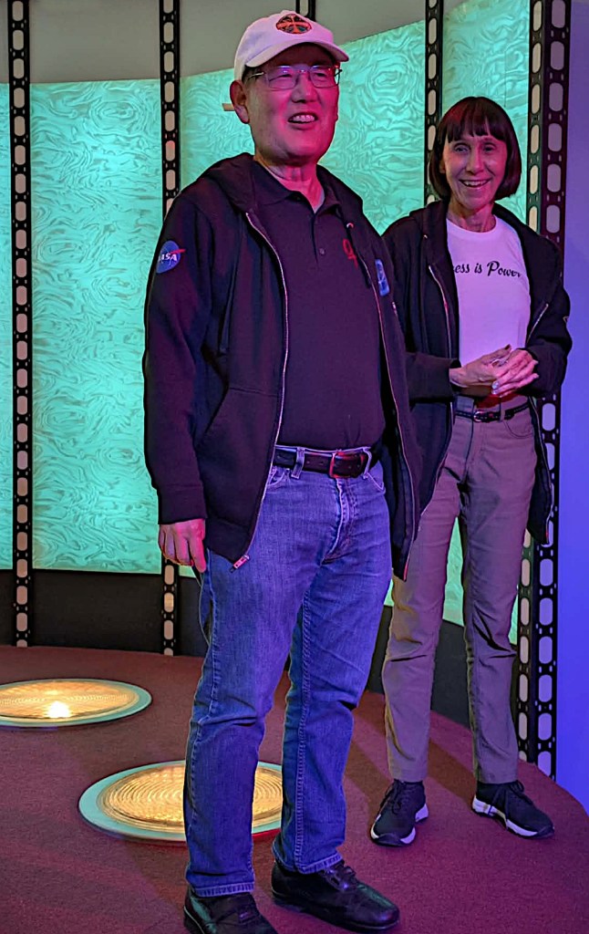 Mike and Denise Okuda standing on the transporter platform at the Set Tour in Septermber 2026.